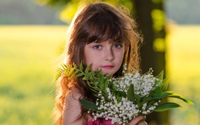 Beautiful little girl with a bouquet of lilies of the valley in hand