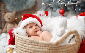 Cute baby in a Santa Claus hat lies in a basket