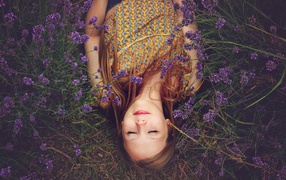 Девочка с закрытыми глазами лежит на земле с фиолетовыми  цветами