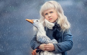 Маленькая девочка блондинка с голубыми глазами с гусем в руках