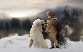 Маленький мальчик с большой белой собакой в лесу 