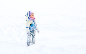 Маленькая веселая девочка гуляет по снегу