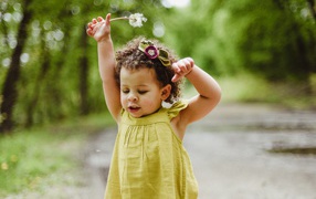 Маленькая девочка в платье с одуванчиком в руке