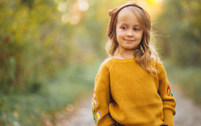 Little girl in a sweater walks in the forest