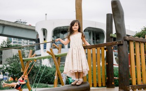 Маленькая девочка стоит на детской площадке 