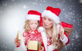 Little girl with mom in Christmas costumes with gifts