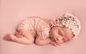 Маленький спящий грудной ребенок в розовом костюме