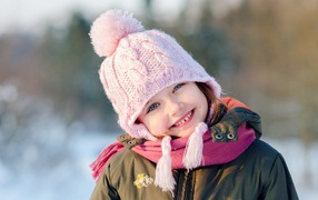 Улыбающаяся девочка в розовой шапке зимой