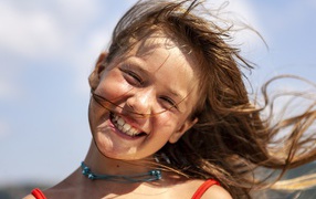 Ветер развивает волосы улыбающейся девочки