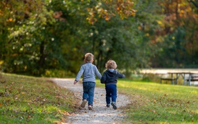 Два маленьких ребенка гуляют в осеннем парке