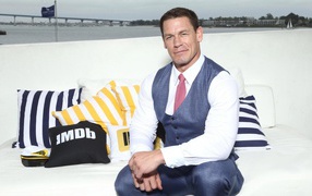 Wrestler John Cena in a suit sitting on a couch