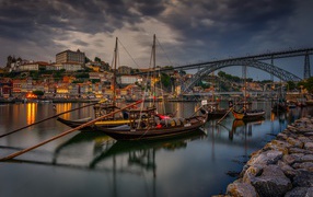 Лодки в порту на фоне моста и города на закате 