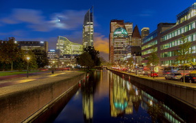 Night skyscrapers are reflected in the water of the canal, the Netherlands