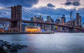 Brooklyn bridge over the river against the background of the night metropolis, USA