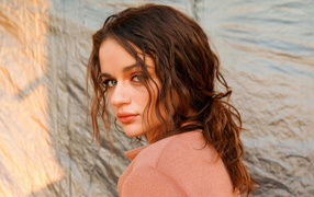 Actress Joey King stands sideways against the wall