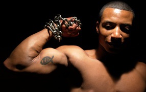 Татуировка на руке у накаченного мужчины на черном фоне