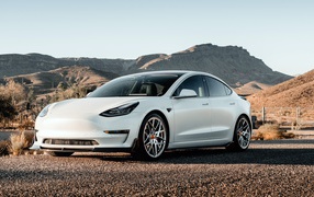 Белый автомобиль Tesla Model 3 Volta 2019 года на фоне гор 
