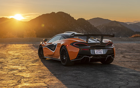 Автомобиль McLaren 620R, 2021 года вид сзади в лучах солнца