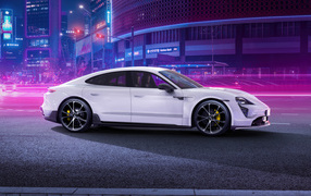 Белый автомобиль Porsche Taycan Aerokit 2021 года в мегаполисе
