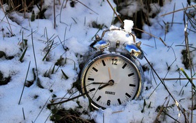 Серебряный будильник лежит в снегу