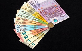 Bundle of euro bills with coin on black table