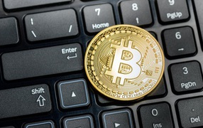 Gold bitcoin coin on black keyboard