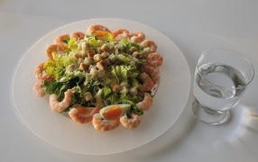 Тарелка аппетитного салата с креветками на столе с рюмкой