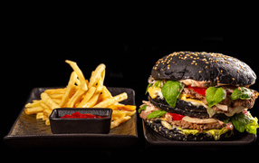 Big black hamburger with fries and ketchup