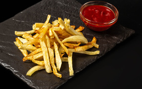 French fries on a stone slab with sauce