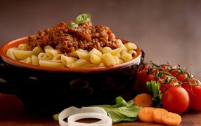 Pasta in a bowl with minced meat on a table with tomatoes