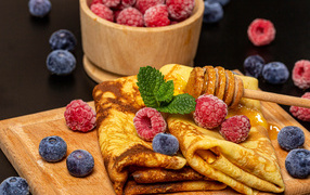 Appetizing pancakes with raspberries and blueberries on the table