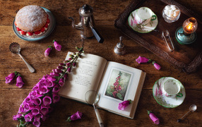 Пирожное на столе с чаем, книгой и цветами 