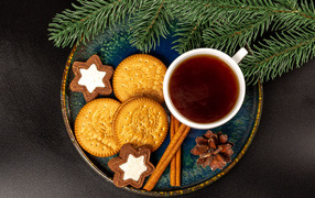 Печенье, чай и корица на столе с еловой веткой