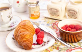 Croissant on a plate with fresh raspberries