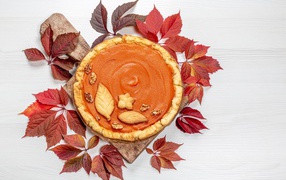 Pumpkin pie with leaves on the table