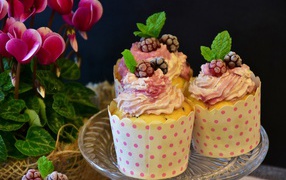 Three cupcakes with cream on a table with flowers