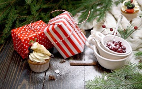 Two gifts on the table with a spruce branch and cupcakes