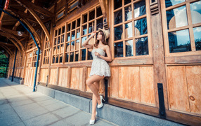 Красивая азиатка в платье стоит у окна кафе