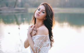 Красивая девушка в белом наряде стоит у озера