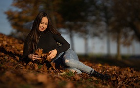 A young girl lies on fallen leaves