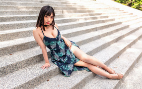 Asian girl in a dress sits on the steps
