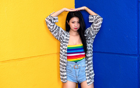 Девушка азиатка стоит у двухцветной стены
