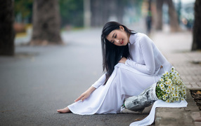 Beautiful Asian girl in a white dress with a bouquet of daisies