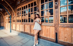 Красивая девушка азиатка стоит у стены с большими окнами