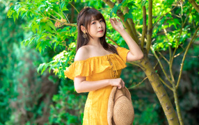 Beautiful asian girl in a yellow dress by the tree