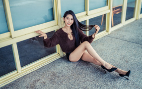 Красивая девушка азиатка в черных туфлях на земле 