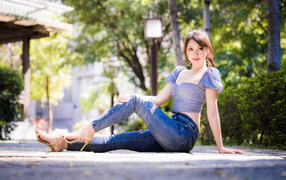 Красивая азиатка в джинсах сидит на земле