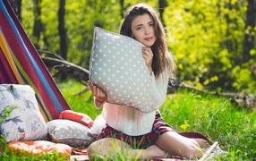 Beautiful girl sitting on the grass with pillows