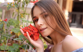 Красивая девушка с красным цветком герани 