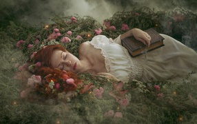Beautiful red-haired girl sleeping on the ground with a book